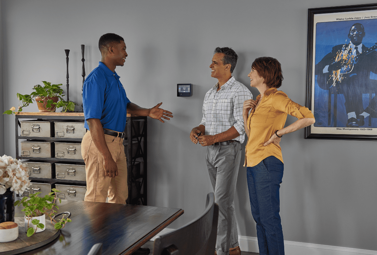 A technician reviewing thermostat and comfort settings with homeowners at home